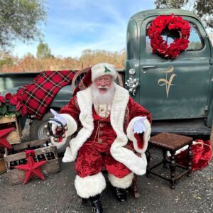 santa claus sitting in front of Little vineyards christmas truck