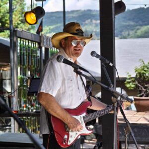 Rich Little on an outdoor stage with a red guitar