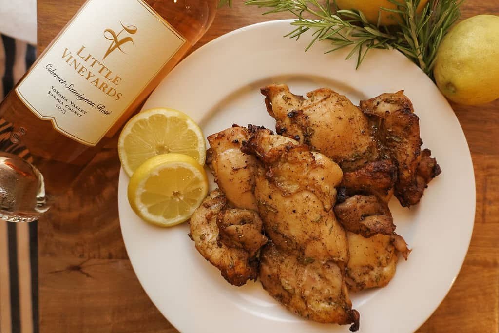 Grilled Herb-Marinated Chicken , with lemon slice garnish and a bottle of Rose on its side. Beautiful plated presentation