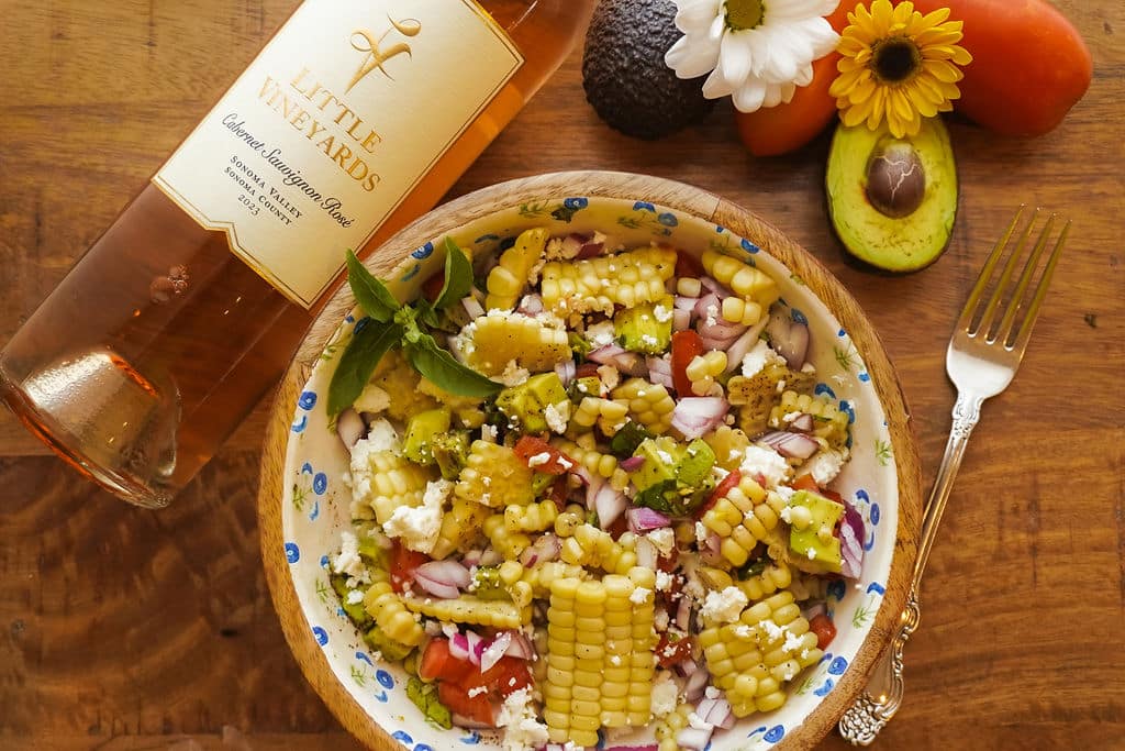 Corn Salad on a plate with bottle of Cabernet Rose on its side next to it.