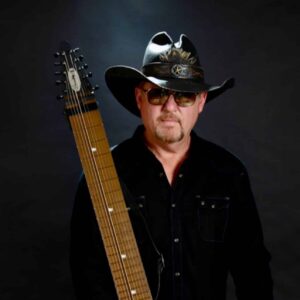 Rich with chapman stick, posed in a studio with a black background