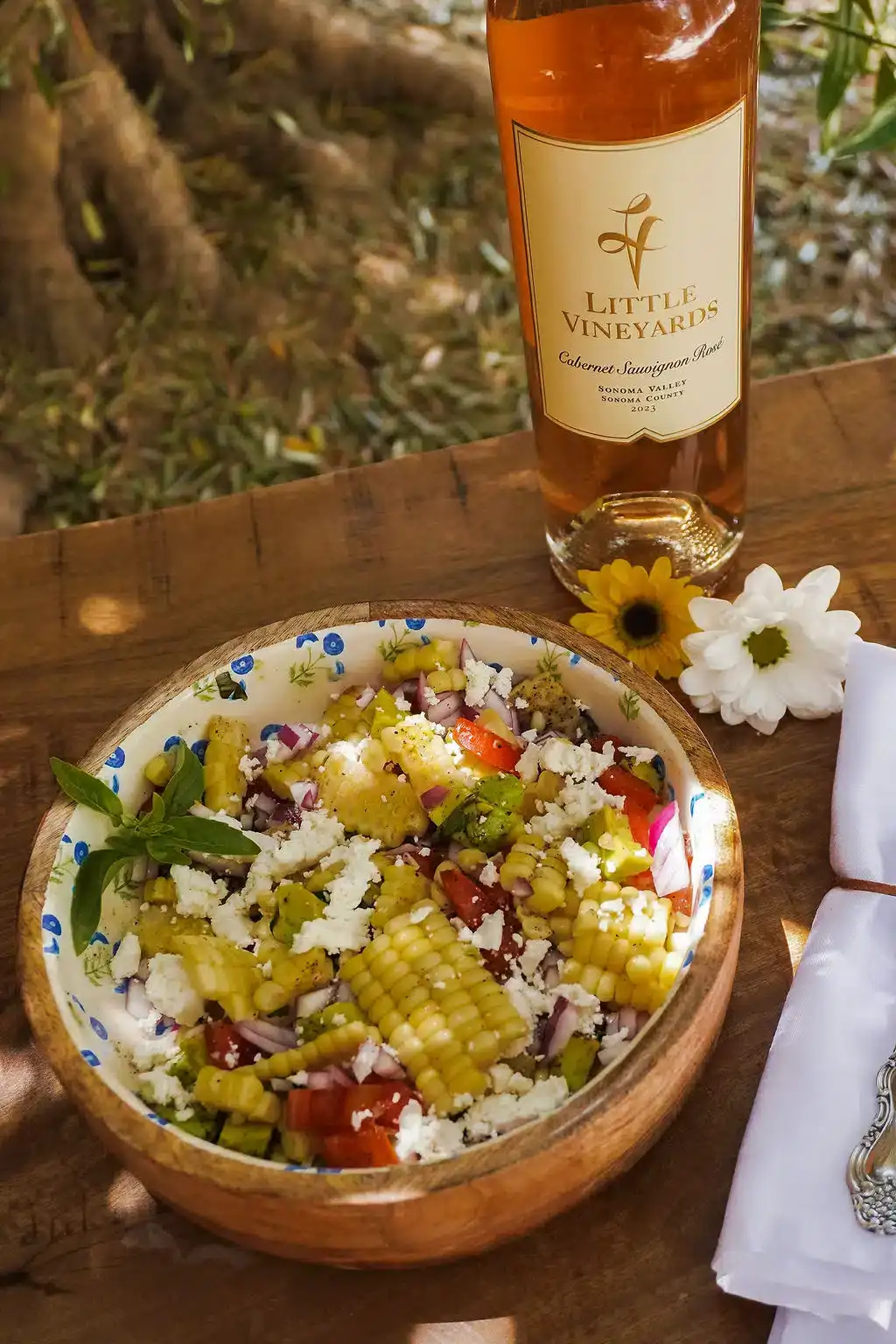 Summer Corn Salad presented on a plate with a bottle of 2023 Rose. Summer and Spring table setting