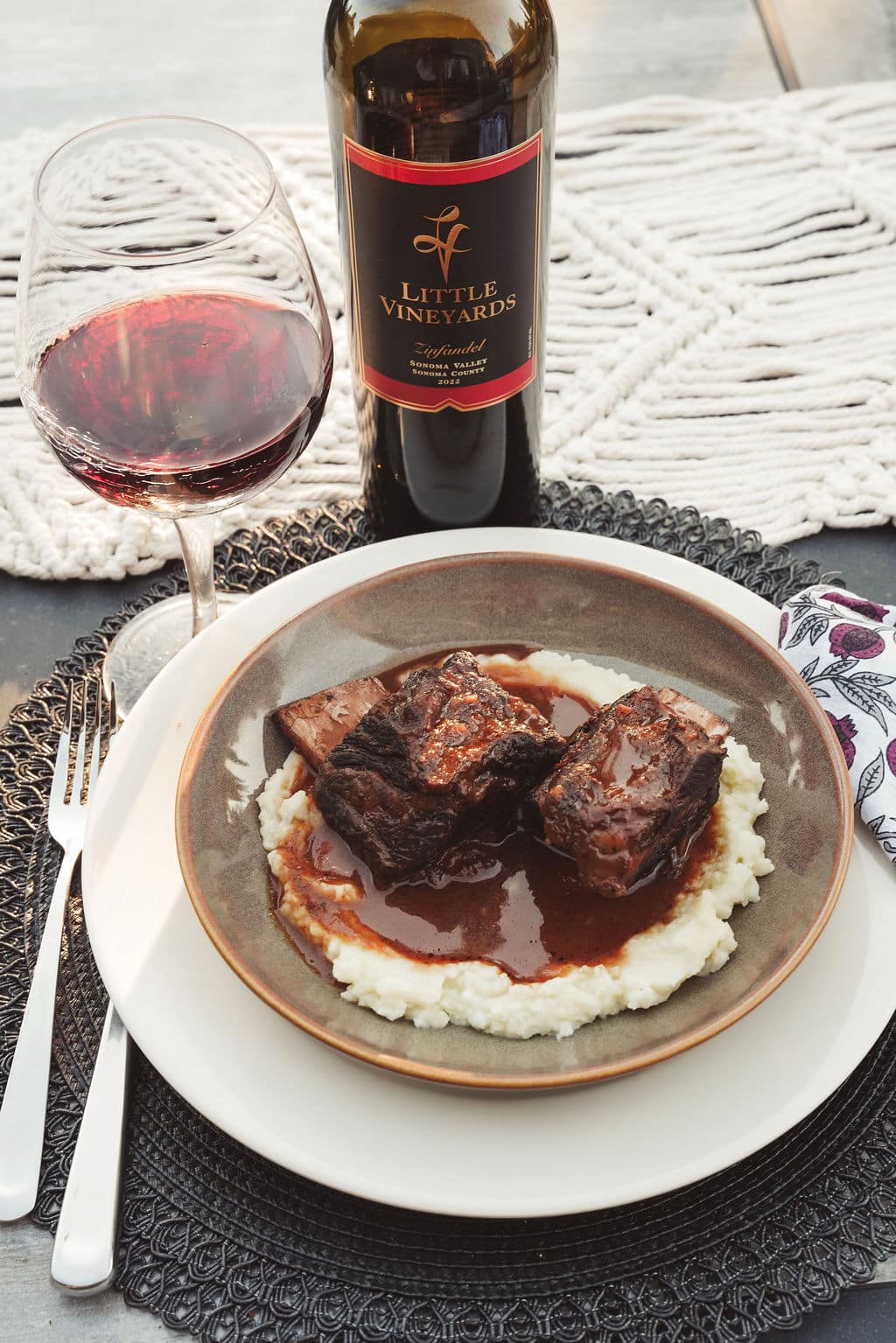 Plated roasted pork with vegetables with a glass of wine and a bottle of bottle in a Fall setting
