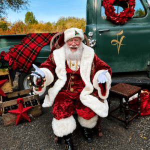 Santa sitting in front of the vintage LV green truck