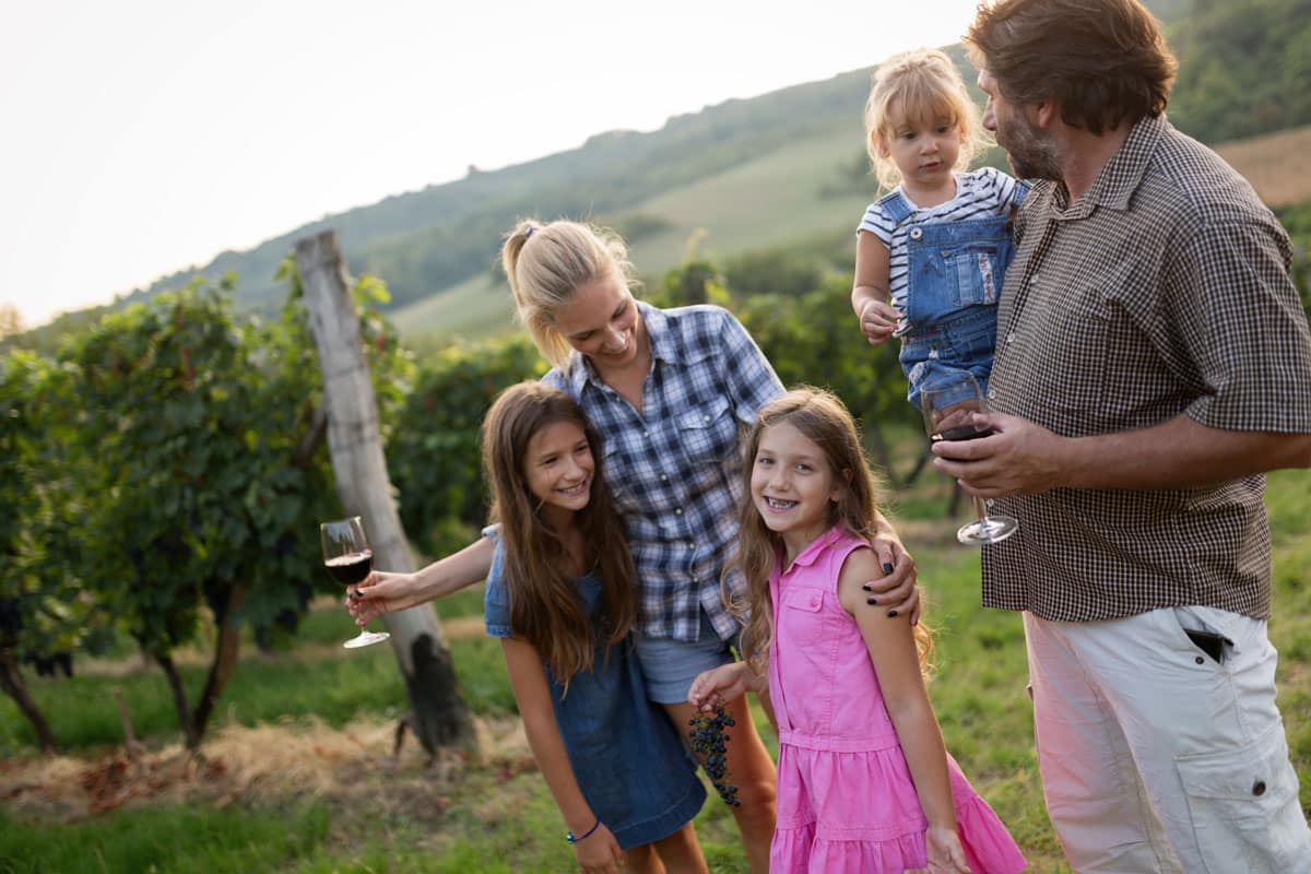 family at a winery in front of a vineyard